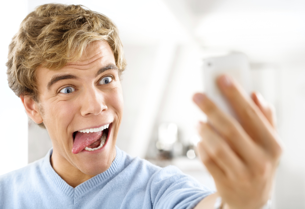 Atractivo joven tomando autorretrato usando teléfono móvil