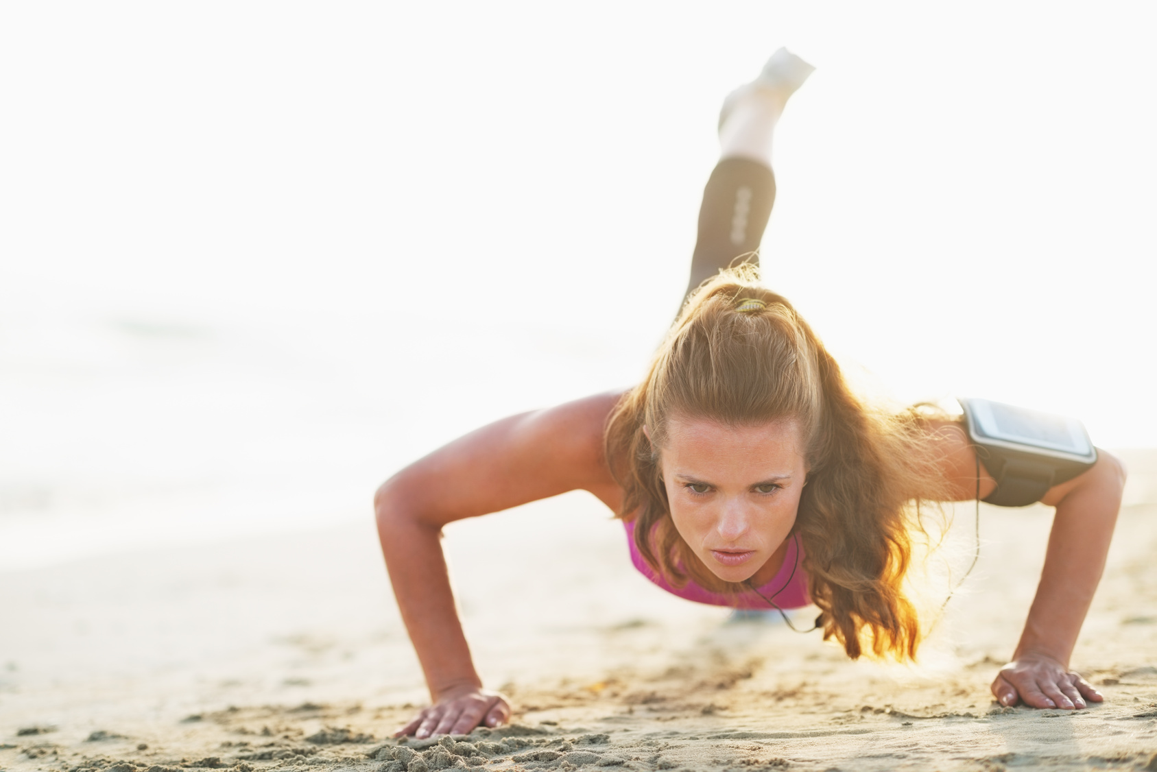 Atleta Femenina haciendo flexiones en la playa